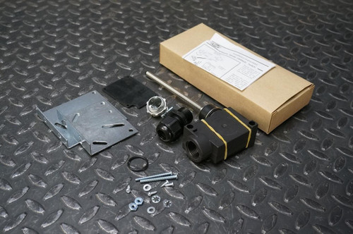 A back-up alarm switch kit, model Preco SWM43C, displayed on a textured metal surface. The kit includes an alarm switch, various screws and bolts, a metal bracket, and a box with installation instructions visible on the lid.