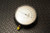 Vintage Ashcroft pressure gauge with a black bezel, white face showing discoloration, and a range of 0-20 inches of water and 0-12 oz/in², featuring a brass connection fitting covered by a yellow protective cap.