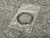 Small clear bag holding a black ring on a gray mat