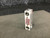 Back of the flowmeter with two threaded ports and a red caution label