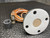 Underside of the round flange with bolt holes and tan transducer face