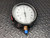 Ashcroft pressure gauge with a 4.5-inch white dial face measuring 50 in. H₂O Vac / 0-50 Pressure, featuring a black housing and a brass bottom connection with a blue protective cap.
