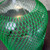 Close-up of the top portion of a glass carboy wrapped in green Poly-Net HDPE Protective Mesh Netting Tube from Obtainium Science and Surplus.