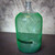 Clear glass carboy covered from shoulder to base by a green mesh netting tube