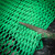 A pair of scissors cutting into green Poly-Net HDPE Protective Mesh Netting Tube from Obtainium Science and Surplus on a dark textured surface.
