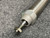 Detailed closeup of the SMC CM2E32200Z Air Cylinder, showcasing its robust brushed silver metallic finish and precision components. This 32mm bore 200mm stroke pneumatic cylinder features a prominent hexagonal end cap with threading, from which an adjustable threaded piston rod extends, secured by a nut. The industrial automation linear actuator component appears durable and highquality, resting on a textured grey surface, with a small green element visible on its body.