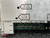 Closeup of a Telewave PM5C1S Automatic Alarm Panel for RF power systems, featuring a brushed silver aluminum front panel with clear black text labels. The panel displays "DELAY ADJUST" and "VSWR  ALARM ADJUST" with corresponding circular adjustment points. Below, a "SENSORS" section is labeled with inputs T1, T2, T3, T4, T5, and ANT (Antenna), each showing Fwd (Forward) and Rev (Reverse) connections. A green circuit board is visible with twelve silver BNCstyle RF connectors arranged in six pairs, indicating detailed RF signal monitoring capabilities for multiple transmitters or an antenna. This industrialgrade RF monitoring and alarm unit is designed for telecommunications and broadcast equipment.