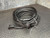Coiled black ruggedized Cat5e cord, braided jacket with red tracer, both RJ45 ends visible and intact, rigged with pull string suggesting conduit-ready preparation.
