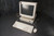 A vintage Sun SPARC workstation setup on a textured dark background, consisting of a bulky CRT monitor, base unit, full-size keyboard, and a connected mouse. All components are beige, with subtle blue branding, reflecting the classic computing aesthetic of the late 20th century.