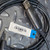 Close-up of the unused Elecraft KXUSB Cable PCX0151 from Obtainium Science and Surplus, showing the USB connector and 3.5mm audio jack with a product tag displaying a barcode on a textured metal surface.