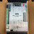 Carrier OPNMPCXP MPC Open XP Automation Controller Module for HVAC from Obtainium Science and Surplus shown inside a cardboard box, displaying its wiring terminals, connectors, and labeled components on the metal faceplate.