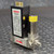 Sierra Mass Flow Controller 840M1V1 for 0–30,000 SCCM of Air, a compact industrial gas flow precision instrument, is shown prominently on a dark diamond plate metal surface. The device features a black rectangular electronic housing with goldplated pin connectors visible on the top edge and a detailed white product label on its side. This label clearly displays "SIERRA INSTRUMENTS INC.", the model number "840M1V1", serial number "C18520", range "030,000 SCCM", and specifies "AIR" as the gas type. Below the black housing is a robust silvertoned stainless steel base block, which includes a red rectangular "FLOW" indicator label with the Sierra logo, multiple visible mounting screws, and threaded fittings for gas input and output connections on the lower right. A brushed metal cylindrical sensor or solenoid component, topped with a bright yellow caution label, is securely attached to the right side of the stainless steel base. This MFC (Mass Flow Controller) is designed for accurate and precise control of gas flow in various industrial and laboratory applications.