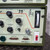 A detailed closeup of the control panel of a Dimetrics Centaur 75 orbital TIG welder, model 7001 or 7008. The olive green industrial welding machine features a light beige front panel with clear labels and controls. Prominent digital display knobs show settings for 'WELD CURRENT' at 166, 'LOW PULSE FREQ.' at 566 (likely 5.66 PPS), and 'BACKGROUND CURRENT' at 190 (likely 19.0 amps), with ranges of 075 AMPS. A vertical analog 'ARC VOLTAGE' meter is visible, along with a 'LOW PULSE' toggle switch and a 'DOWNSLOPE' control knob. The lower section includes 'REMOTE OUT' and 'REMOTE IN' Dsub connectors, a 'GROUND' port, and a red 'AC POWER' rocker switch in the off position. The panel also displays the '75' model identifier and a centaur illustration, highlighting this precision welding power source.