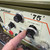 Detailed view of the control panel of a Dimetrics Orbital Welding Centaur 75 TIG Welder, specifically highlighting the 7001 or 7008 model. The creamcolored panel with an olive green top casing features multiple black rotary knobs with clear digital readouts, including '166' for 'WELD CURRENT' and '5643' for 'LOW PULSE FREQ.'. A finger is shown adjusting one of these precise control dials, which also displays '0.999' for 'LOW PULSE WIDE', illustrating the machine's advanced settings for industrial welding applications.