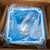 The Meltric wall box and 70-degree angle adapter packaged inside a cardboard box, with its blue plastic cover still wrapped in protective plastic. The enclosure is secured for shipping.