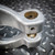 Unused Crosby S-1325A Chain Coupler, 1/2-13, Grade 100. Close-up of metallic links with pin holes on a diamond plate.