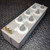 Angled view of a General Radio GenRad 1433-F Decade Resistor Box from Obtainium Science and Surplus, showing six gray dials on a rectangular metal enclosure with brass connectors on one end.
