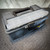 Closed gray plastic toolbox with a black handle and transparent top compartment, resting on a textured floor. Conval TK5D-C-S-1 Tool Kit for Size 5D Valves from Obtainium Science and Surplus.