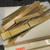 Loose pile of gold-plated edge connector strips on Ohaus scale; gold contact fingers intact, green fiberglass substrate visible, surface oxidation and dirt present throughout.