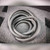 Gray rubber hose coiled loosely; surface shows light dust and minor scuffs. Partial text visible on outer wrap near top of coil.