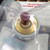 Cylindrical galvanic micro-fuel cell with brushed brass top face, dark red dome-shaped membrane, two small terminal contacts, and partial label reading A-5 and code K9.