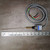 Gray-jacketed 4-conductor cable with black, red, green, and white leads. gold-zinc coil spring at actuator base; slender wobble rod extends roughly 7 inches per ruler.