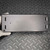 Matte dark gray metal enclosure bottom face, no markings visible. Light scuff marks near center. Two mounting slots per side, two small holes on face.