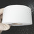 Matte white roll with cardboard core visible, no markings on outer face, uniform wound edges, no visible damage.