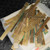 Pile of mixed short and long gold-plated finger strips on a scale, including green solder-mask pieces and a strip with blue tape