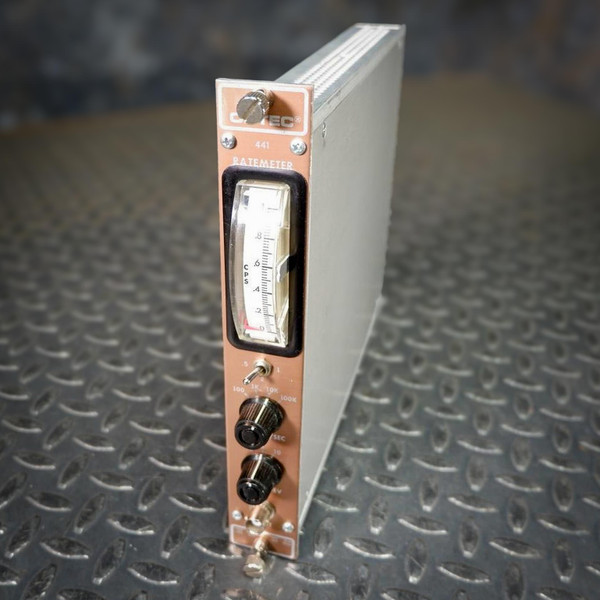 Oblique view of a NIM BIN Module - Ortec 441 Linear Count Ratemeter from Obtainium Science and Surplus, showing the front panel with a curved analog meter display, adjustment knobs, and labeled controls, set on a diamond-plate metal surface.