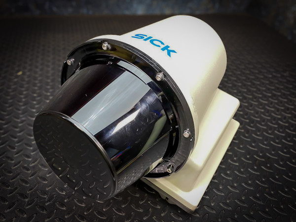 SICK LiDAR sensor angled to show its round black window and bolted ring