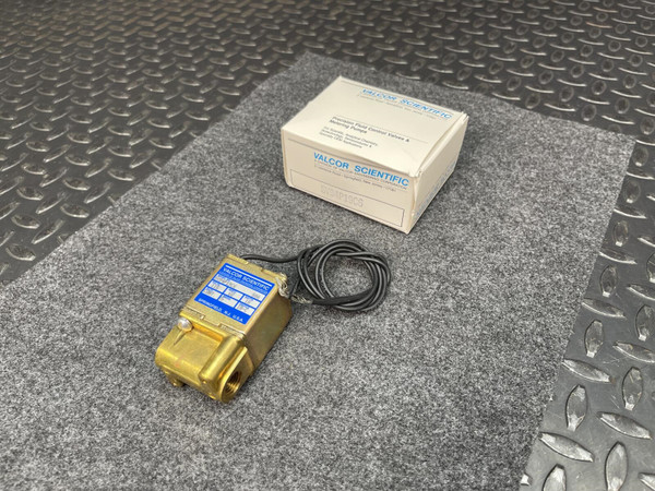 Valcor Scientific SV94P19C6 solenoid valve with wires, brass body, and original packaging on a gray mat.