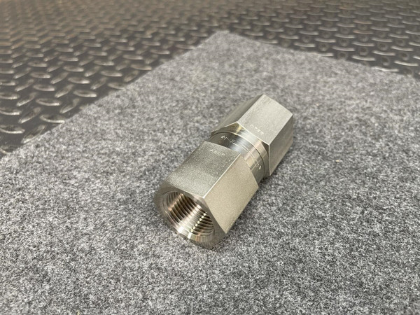 Swagelok Nupro 316 stainless steel check valve with 1.25 inch FNPT connections on a gray surface.