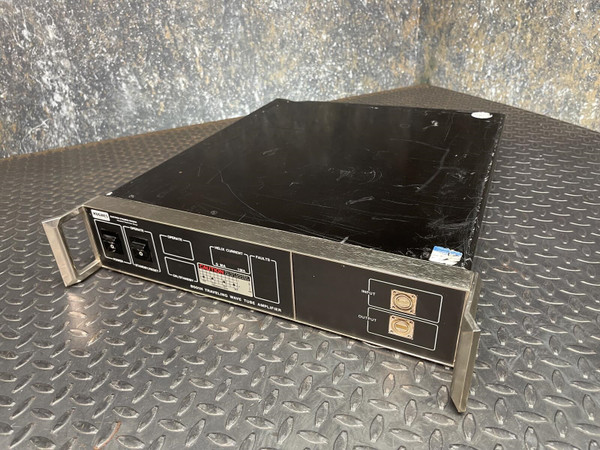 Hughes 8001H TWTA 1 W Ku/K-Band RF Power Amplifier from Obtainium Science and Surplus, shown in full view on a textured metal floor, with a black rectangular chassis and front panel featuring various controls and connectors.