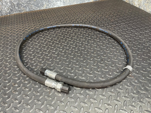CAT Caterpillar 8N1186 hydraulic hose coiled on a diamond plate, showing silver fittings with black caps.