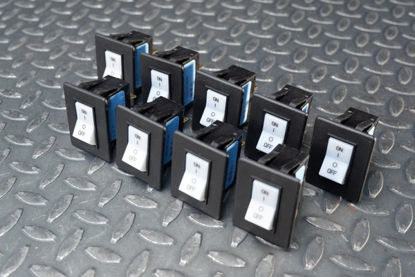 Nine black rocker units arranged in rows; white rockers labeled ON/OFF visible, blue accent color on bodies. No visible wear or damage.