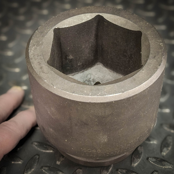 Unused Proto 15048 3" Impact Socket from Obtainium Science and Surplus shown resting on a textured metal surface with a hand nearby for scale; the large six-point opening is visible.