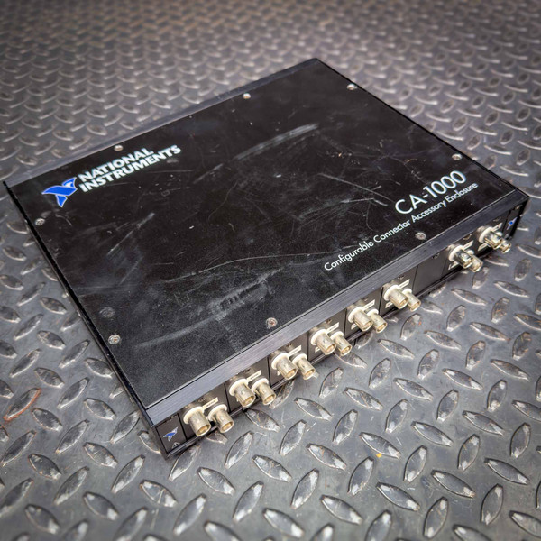 National Instruments CA-1000 enclosure with multiple connector ports on the front, placed on a textured metal surface.