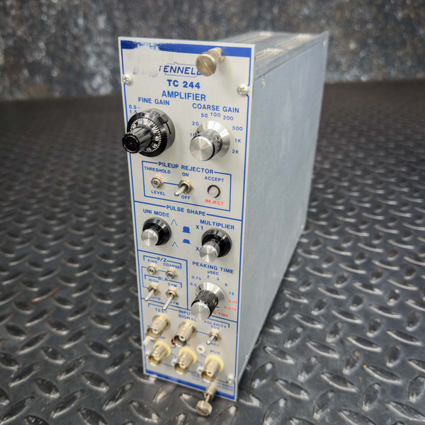 Front angled view of the Tennelec TC 244 Spectroscopy Amplifier NIM BIN module from Obtainium Science and Surplus, showing its various control knobs, input/output ports, and labels on the metal casing.
