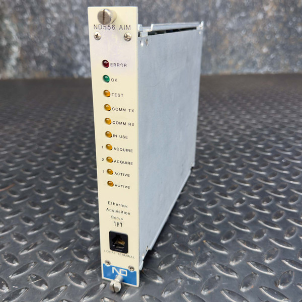 A side angle view of a Canberra ND556 Acquisition Interface Nuclear Instrumentation Module from Obtainium Science and Surplus, showing its narrow rectangular shape with multiple indicator lights and labels on the front panel.
