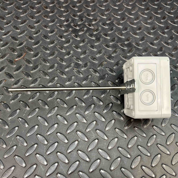 Side view of the Duct Temperature Sensor by Automation Components from Obtainium Science and Surplus, featuring a rectangular enclosure with a metal probe extending from one side, placed on a textured metal background.