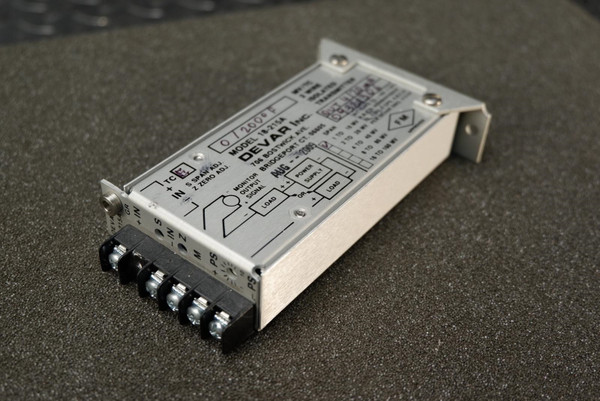 A Devar thermocouple transmitter placed on a dark foam surface, displaying part of its wiring terminals and metal casing.