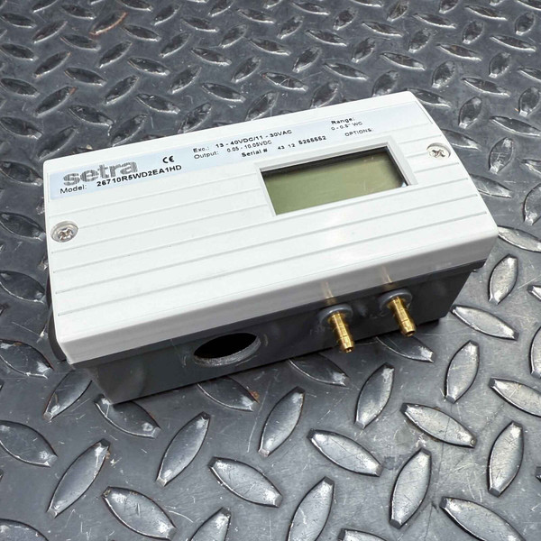A Setra Systems 267 Low Differential Pressure Sensor from Obtainium Science and Surplus, resting on a textured metal surface. The device has a rectangular metal body with a small LCD screen and two brass pressure ports.