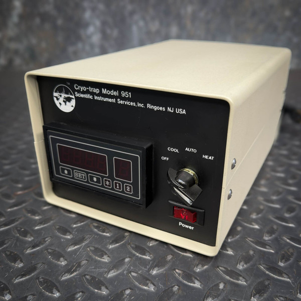 SIS CryoTrap Controller Model 951 from Scientific Instrument Services, a creamcolored benchtop laboratory instrument with a black front panel featuring two red LED digital displays, control buttons (up arrow, SET, down arrow, asterisk, 1, 2), a multiposition rotary switch for COOL, OFF, AUTO, and HEAT modes, and a red illuminated power rocker switch. This compact precision temperature control unit for CO2 cryotraps is shown at an angle on a dark industrial diamond plate background, highlighting its scientific instrument details.