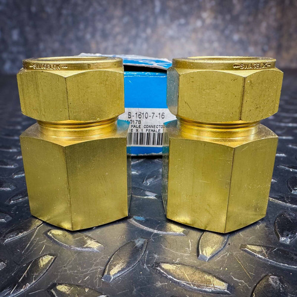 Two Swagelok B-1610-7-16 1 inch brass female connectors on a metal surface, showing the packaging label.