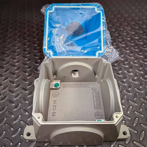 An open Meltric wall box and 70-degree angle adapter for use with DSN60, DS30, and DR50 Series from Obtainium Science and Surplus. The gray metal enclosure is placed on a textured surface, with a blue gasketed cover partially open and covered in protective plastic.