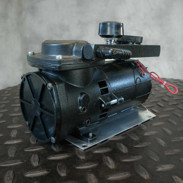 Thomas diaphragm vacuum pump showing black textured finish with minor scuffs, red power leads tied, mounted on clean aluminum base plate.