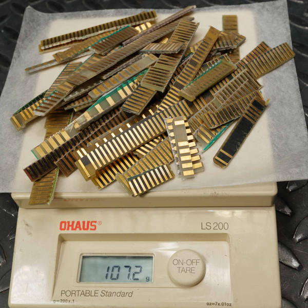 Lot of mixed gold-finger edge connectors weighing on Ohaus LS 200 scale. Varied lengths; oxidation and patina visible on several pieces.