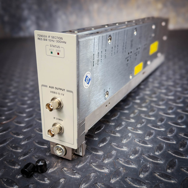 Front panel marked 70902A IF SECTION, RES BW 10Hz-300kHz; ACT and ERR status LEDs present; AUX OUTPUT with VIDEO 0-1V and IF 3MHz BNC connectors; HP calibration sticker on chassis side; two yellow labels on top; two loose black plastic caps nearby.