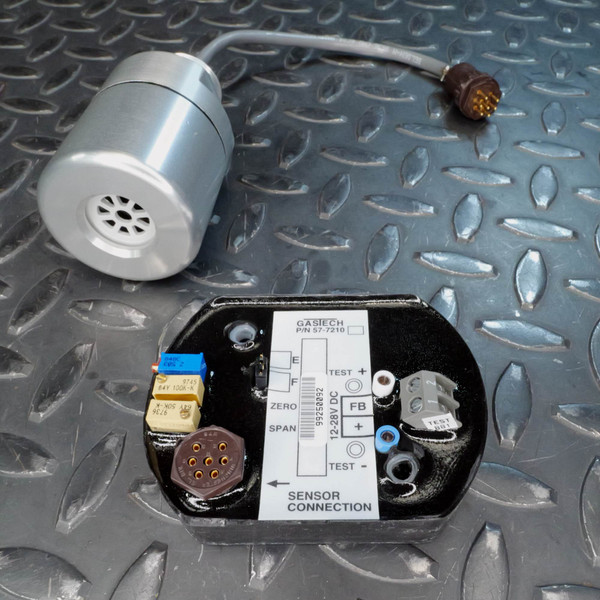 Label reads GASTECH P/N 57-7210, 12-28V DC, with ZERO and SPAN trimmers, TEST+/- points, and FB marked. Sensor housing attached via cable with gold-pin receptacle.